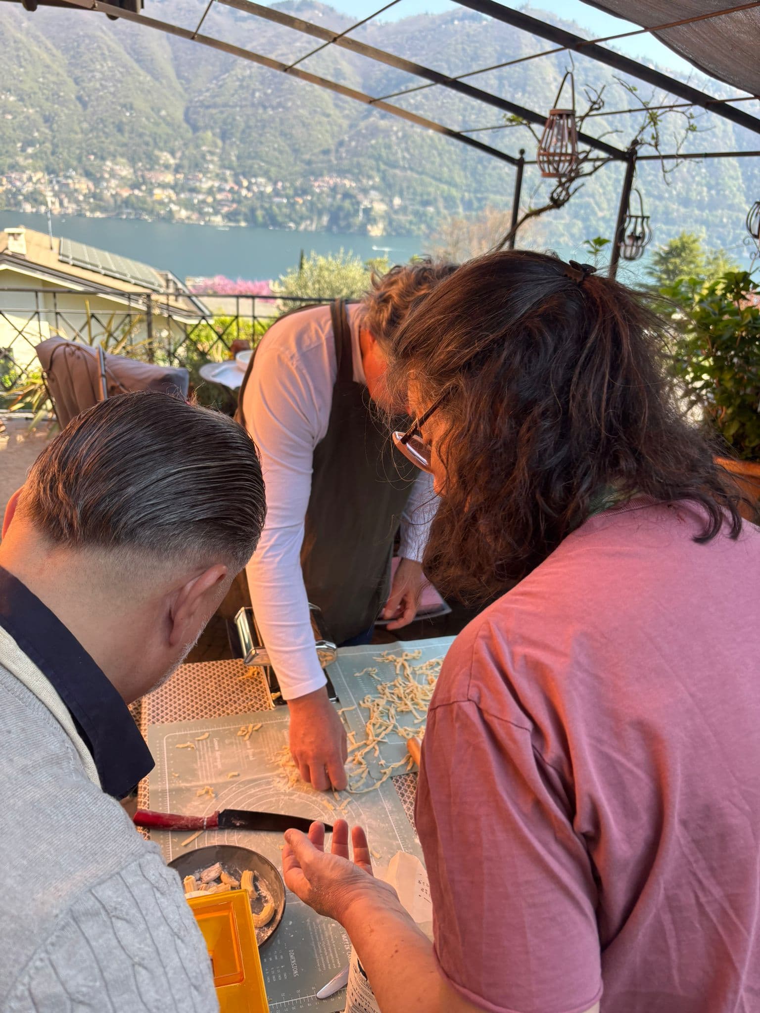 Participants making pasta together outdoors with a lake view
